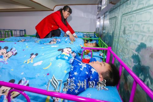 学生在午托机构午休，工作人员为孩子们盖好被子。